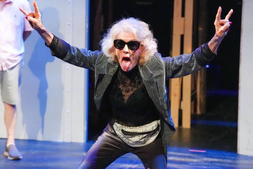 A performer in sunglasses throwing rock horns to the audience in Romeo and Juliet: Forever